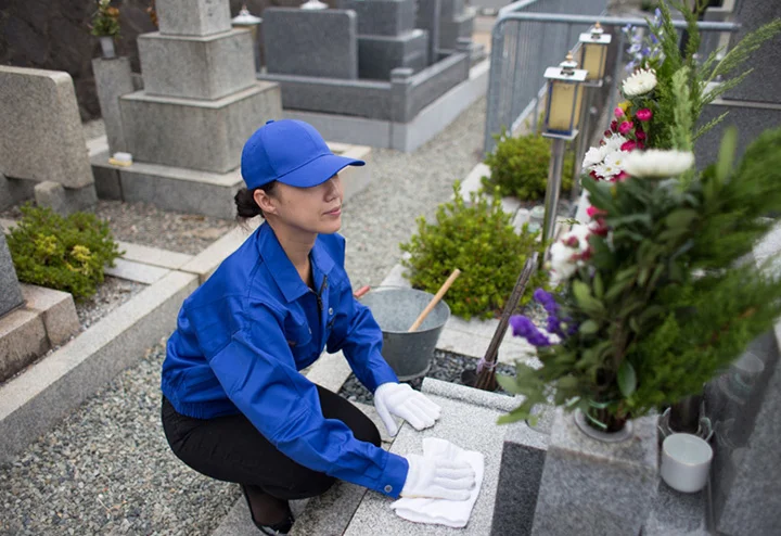 女性スタッフが墓石を掃除している