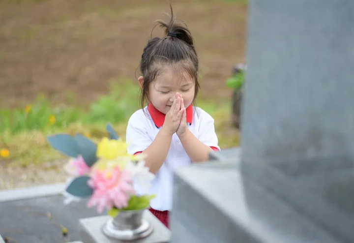 子供がお墓参りをしている写真